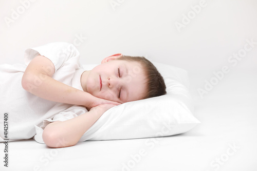 portrait of a cute little boy sleeping on a white pillow isolated on a white background. fresh and cozy bedding sheets. Bedtime for kids. concept of happy dreaming