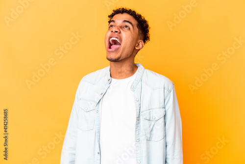 Young african american curly man isolated on purple shouting very angry, rage concept, frustrated.