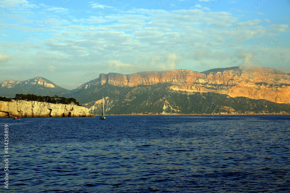 Sailboat on the blue sea with the background of the coast and mountains, Parc National des Calanques, Marseille, France
