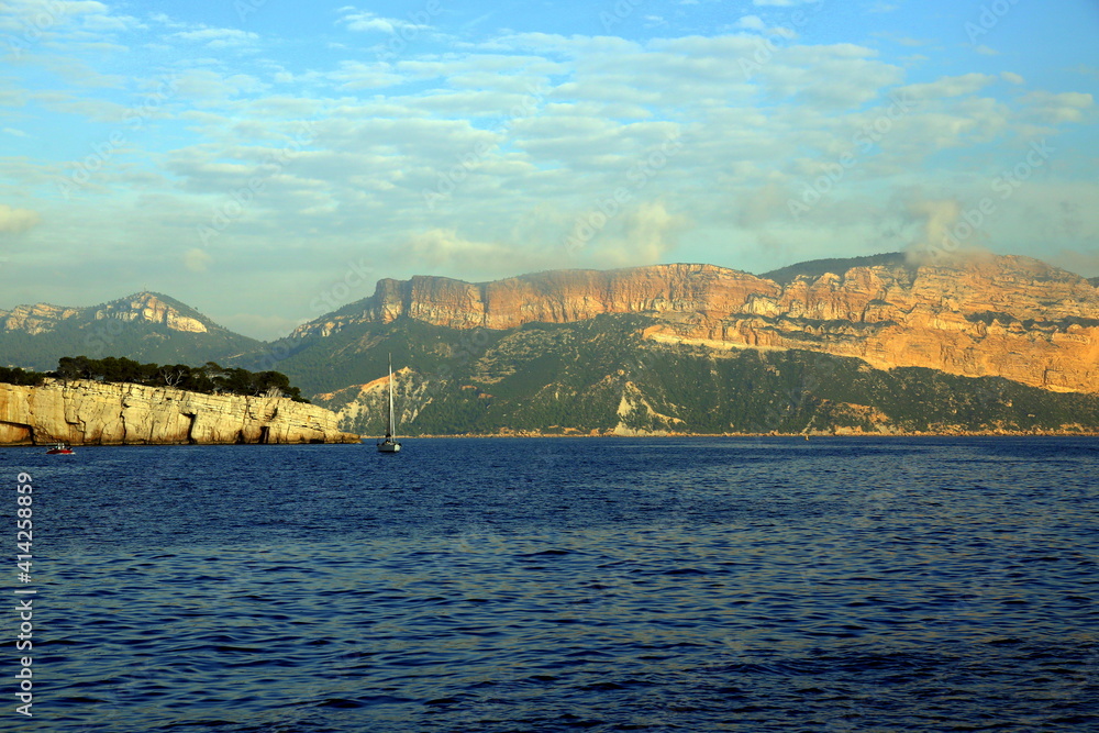 Fototapeta premium Sailboat on the blue sea with the background of the coast and mountains, Parc National des Calanques, Marseille, France