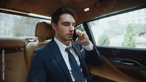 Portrait of handsome business man calling on smartphone in comfortable car. © stockbusters