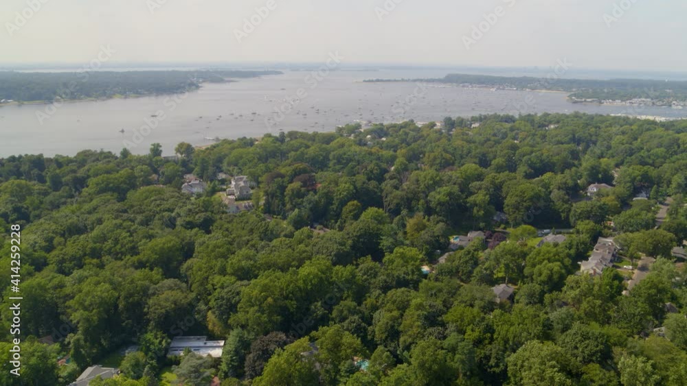 Aerial Pan of a Small Town Amongst Trees and Boats on Bay Seen from a Distance Aerial Pan of a Small Town Amongst Trees and Boats on Bay Seen from a Distance