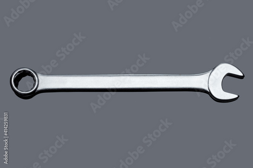 silver spanner wrench iron hand tool for repair and service plumbing instrument isolated on gray glass background with reflection top view, nobody.