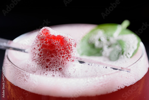 Raspberry rum cocktail with raspberry and basil garnish and foamy top