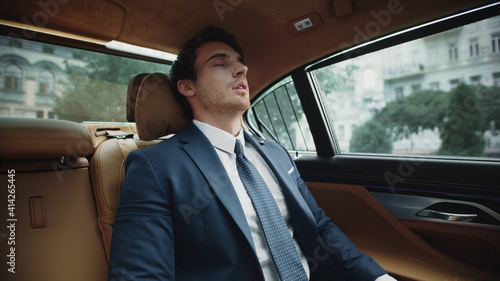 Portrait of exhausted business man having rest in back seat of luxury car. © stockbusters
