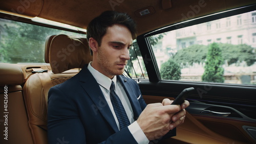 Annoyed business man typing message in cellphone car. Male ceo working in car. © stockbusters