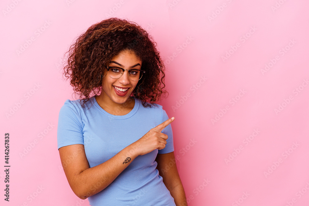 Young african american woman isolated on pink background smiling and pointing aside, showing something at blank space. Young african american woman isolated on pink background smiling and pointing aside, showing something at blank space.