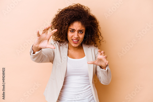 Young african american woman isolated on beige background upset screaming with tense hands.