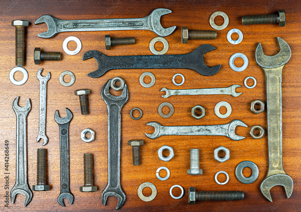 Different wrenches, bolts, nuts and washers on a brown wood texture background Different wrenches, bolts, nuts and washers on a brown wood texture background