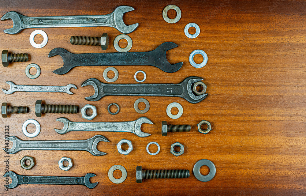 Different wrenches, bolts, nuts and washers on a brown wood texture background Different wrenches, bolts, nuts and washers on a brown wood texture background