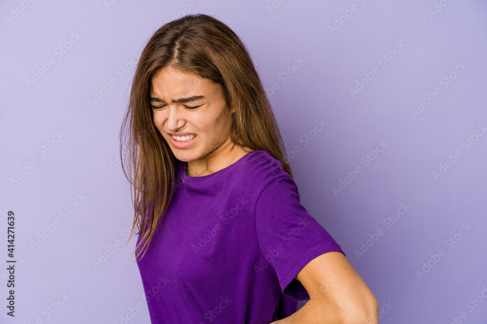 Young skinny caucasian girl teenager on purple background suffering a back pain. Young skinny caucasian girl teenager on purple background suffering a back pain.