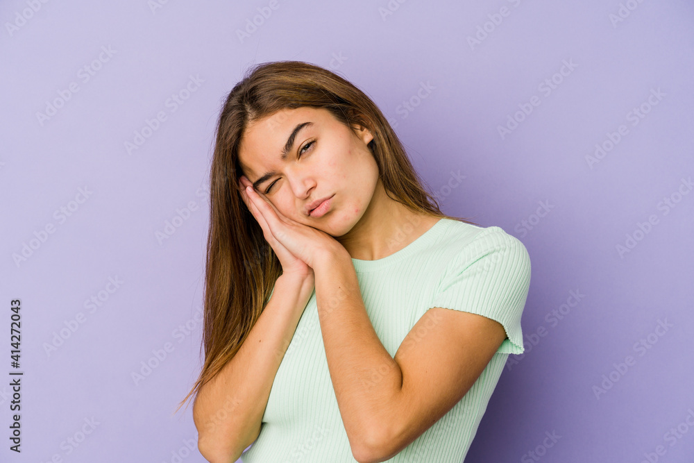 Young skinny caucasian girl teenager on purple background yawning showing a tired gesture covering mouth with hand.