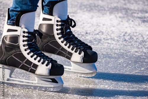 Detail of the black and white mens ice skates in action on ice