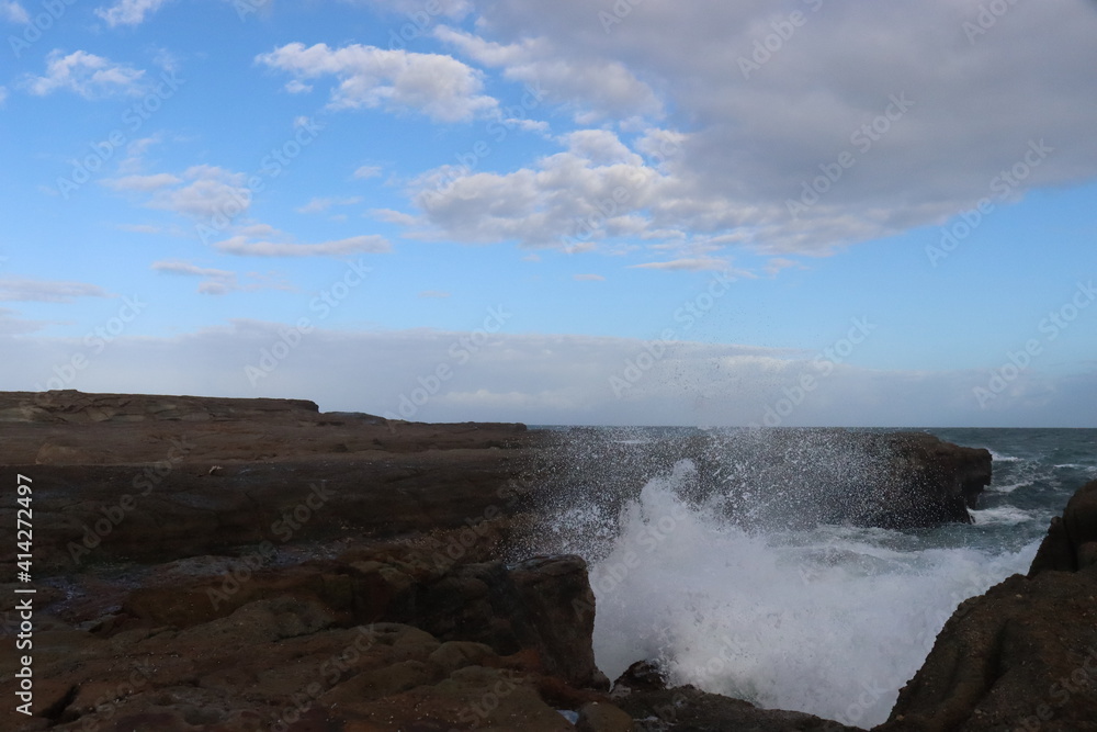 Sea waves impacts on this rock platform down below from the Norah head lighthouse in Central Coast Australia. Blue and white sky formations in the horizon. Sea waves impacts on this rock platform down below from the Norah head lighthouse in Central Coast Australia. Blue and white sky formations in the horizon.