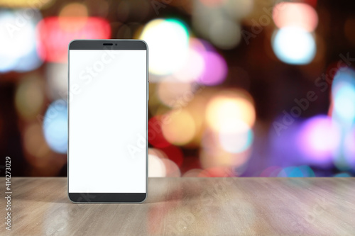 Blank white smartphone screen with place for your sign on wooden table at blurry background. Mockup