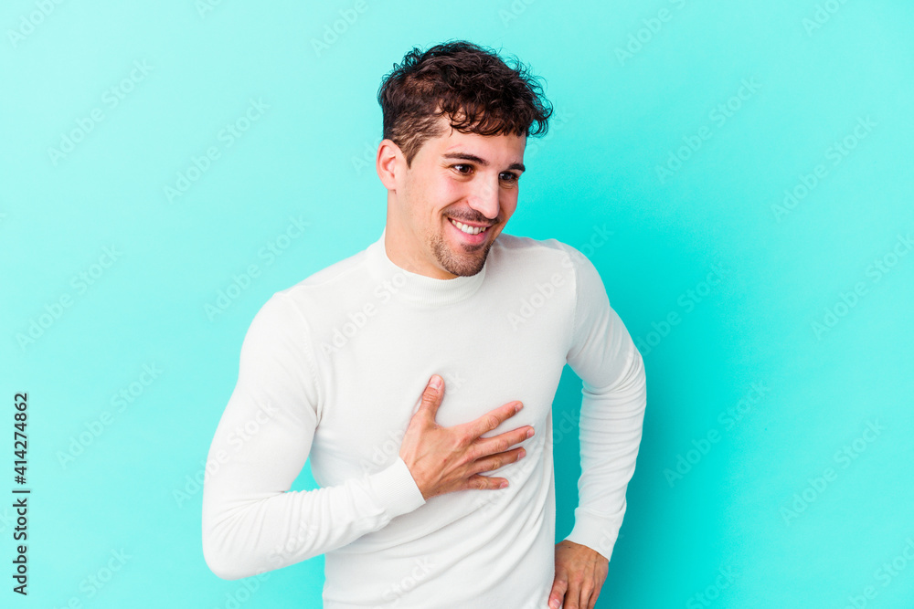 Young caucasian man isolated on blue background laughing keeping hands on heart, concept of happiness. Young caucasian man isolated on blue background laughing keeping hands on heart, concept of happiness.