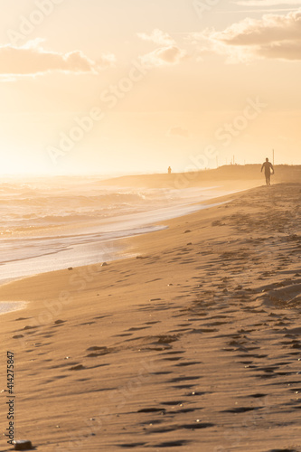 Surfer on the beach running during the sunset