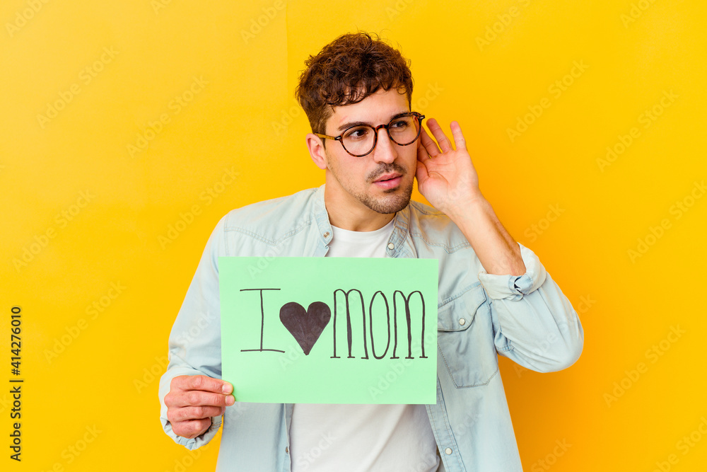 Young caucasian man holding a protect our planet placard isolated trying to listening a gossip. Young caucasian man holding a protect our planet placard isolated trying to listening a gossip.
