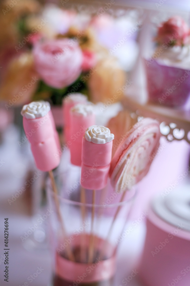 Delicious wedding reception candy bar, dessert table. Pink Sweet table with roses flowers, cupcakes for birthday party. Festive decor in restaurant. Anniversary dating celebration. Delicious buffet
