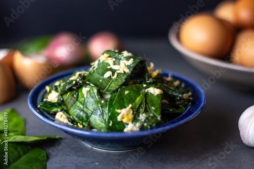 Stir-fried Malindjo leaves with Egg on dark background. (Thai name is Bai Lieng Pad Kai),the leaves is local plant of Southern Thailand, believe it is healthy food photo