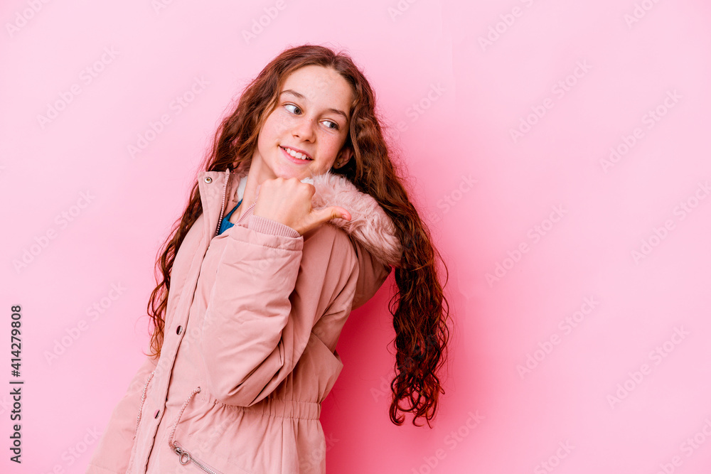 Little caucasian girl isolated on pink background points with thumb finger away, laughing and carefree. Little caucasian girl isolated on pink background points with thumb finger away, laughing and carefree.