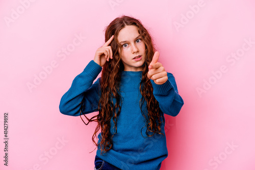 Little caucasian girl isolated on pink background pointing temple with finger, thinking, focused on a task. © Asier