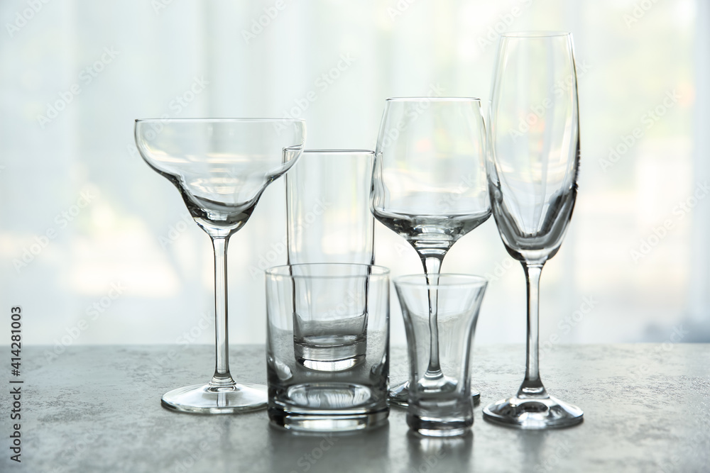 Different elegant empty glasses on grey table indoors Different elegant empty glasses on grey table indoors