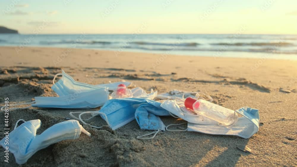 Face masks and hand sanitizer bottle waste discarded on sea shore ecosystem on sunset time,covid19 debris pollution contamination Face masks and hand sanitizer bottle waste discarded on sea shore ecosystem on sunset time,covid19 debris pollution contamination