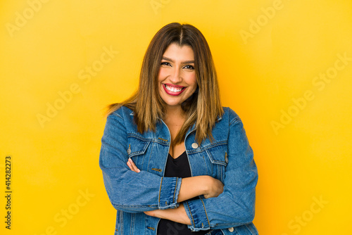 Young indian woman isolated on yellow background who feels confident, crossing arms with determination.