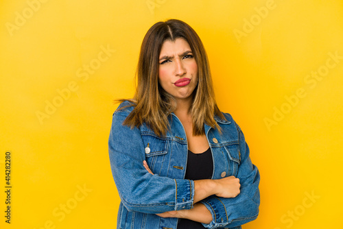 Young indian woman isolated on yellow background suspicious, uncertain, examining you.