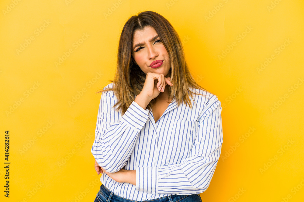 Young indian woman isolated on yellow background suspicious, uncertain, examining you. Young indian woman isolated on yellow background suspicious, uncertain, examining you.
