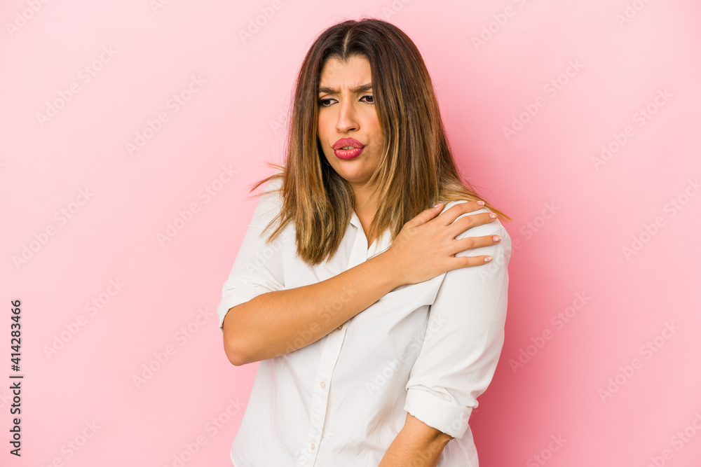 Young indian woman isolated on pink background having a shoulder pain. Young indian woman isolated on pink background having a shoulder pain.