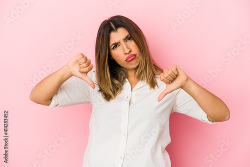 Young indian woman isolated on pink background showing thumb down, disappointment concept.