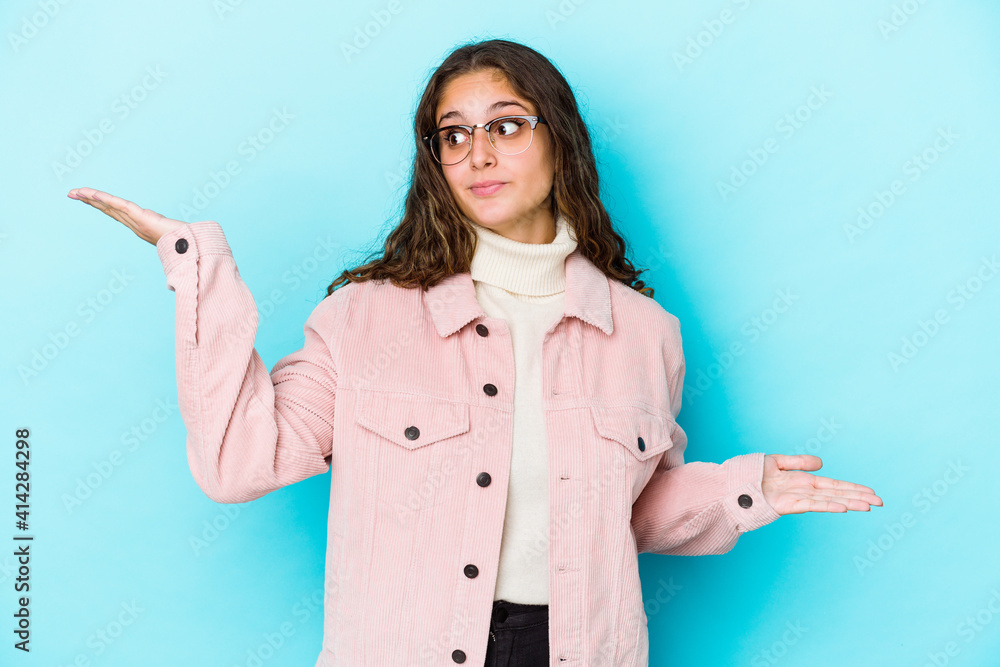 Young caucasian curly hair woman isolated confused and doubtful shrugging shoulders to hold a copy space. Young caucasian curly hair woman isolated confused and doubtful shrugging shoulders to hold a copy space.