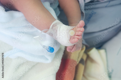 newborn baby's leg wrapped in a cotton swab and a needle for medication.