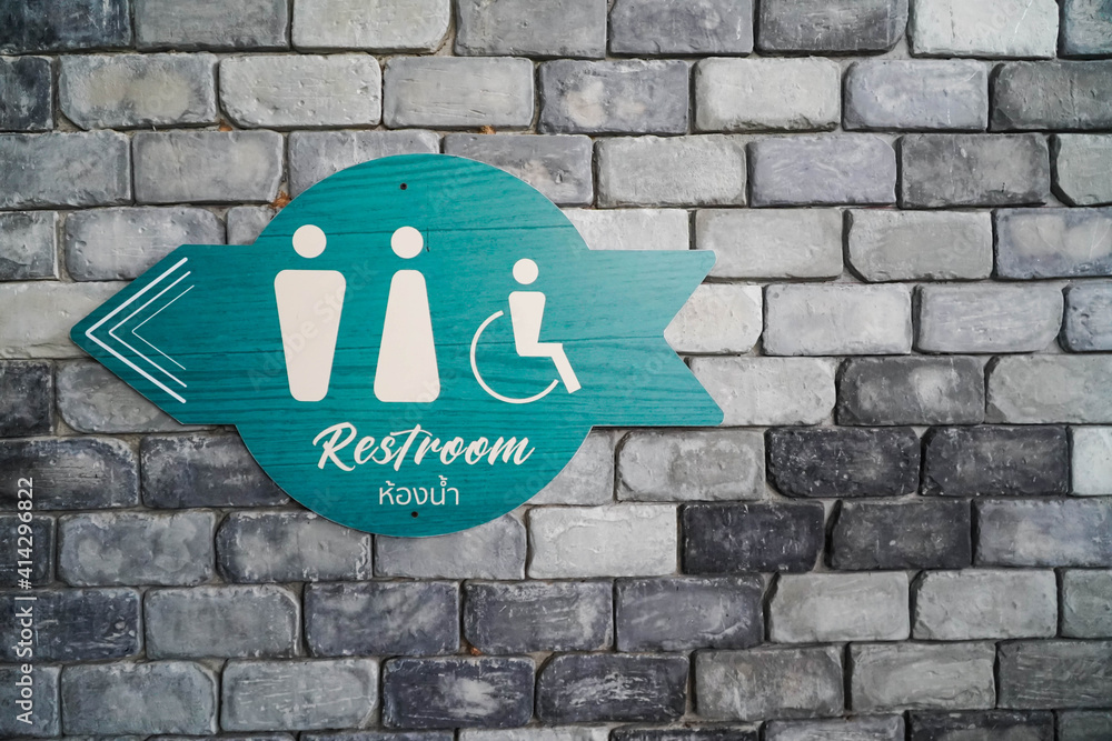 WC - Toilets icon, Public restroom sign with a male and female symbol and direction on a brick wall background. WC - Toilets icon, Public restroom sign with a male and female symbol and direction on a brick wall background.