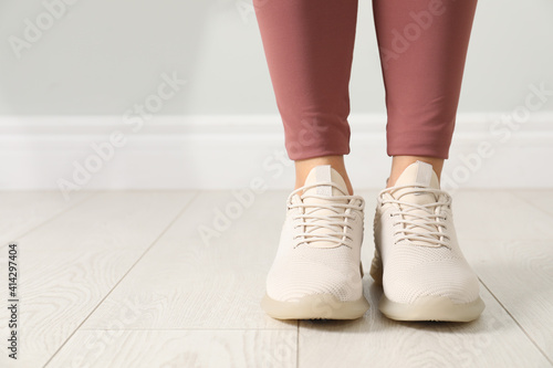 Woman in comfortable stylish sport shoes indoors, closeup. Space for text