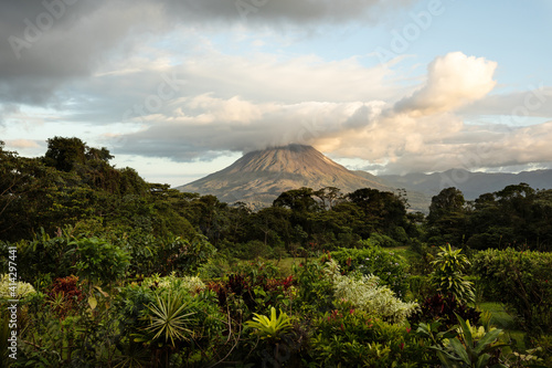 Dramatic photo of Arenal volcano with tropical vegetation in front during sunset. Costa Rica. photo