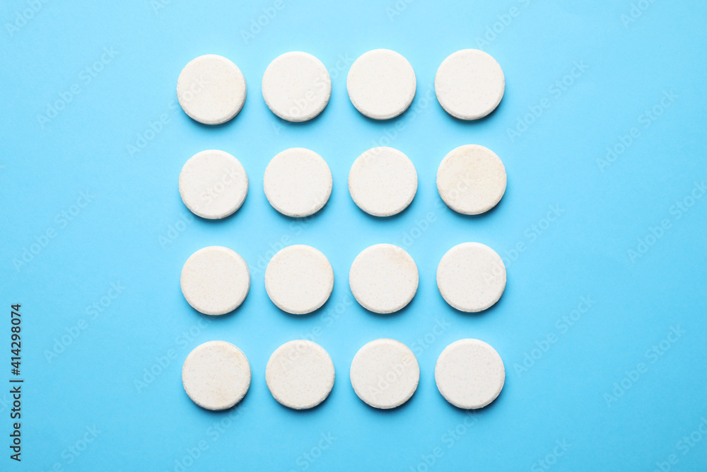 White pills on light blue background, flat lay White pills on light blue background, flat lay