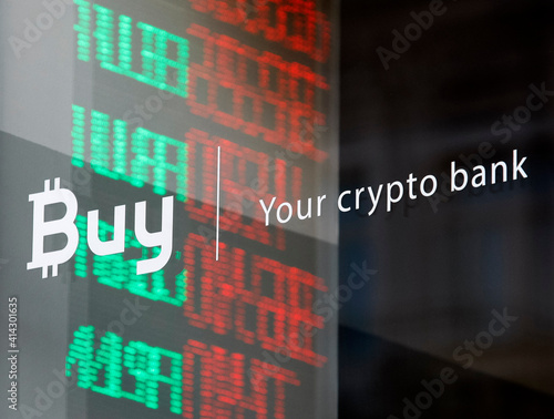 words Buy Your crypto bank on a office window on the background of glowing currency exchange rates on a window of a crypto bank office, in Kiev, Ukraine, on 22 October 2018. photo