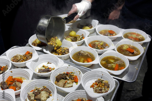a man pouring soup in plastic plates сlose up, iftar dinner coocking
