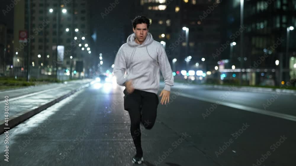 Cinematic shot of young male sportsman with athletic body is running with effort and dedication in city center with snow falling at night. Concept of determination, motivation and goal achievement. Cinematic shot of young male sportsman with athletic body is running with effort and dedication in city center with snow falling at night. Concept of determination, motivation and goal achievement.