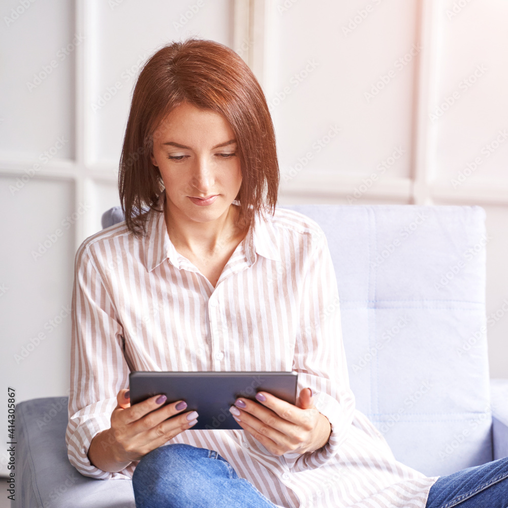 Young woman sitting at chair. Working on tablet. Online study concept. Safety lockdown distance teaching. Female person. Quarantine office. Business writer. Video relax Young woman sitting at chair. Working on tablet. Online study concept. Safety lockdown distance teaching. Female person. Quarantine office. Business writer. Video relax