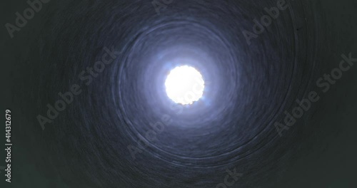 Moving through a tube tunnel with bright light shining at the end, probe lens motion, rising in shaft photo