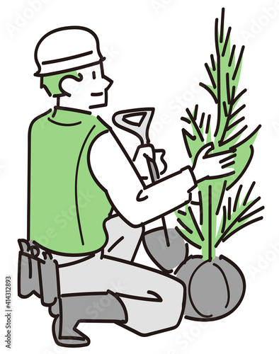 スコップを持って植樹作業をしている造園業の男性