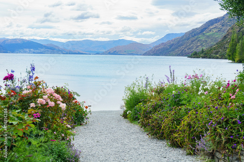 Shingle path between roses and wildflowers leading to lake edge