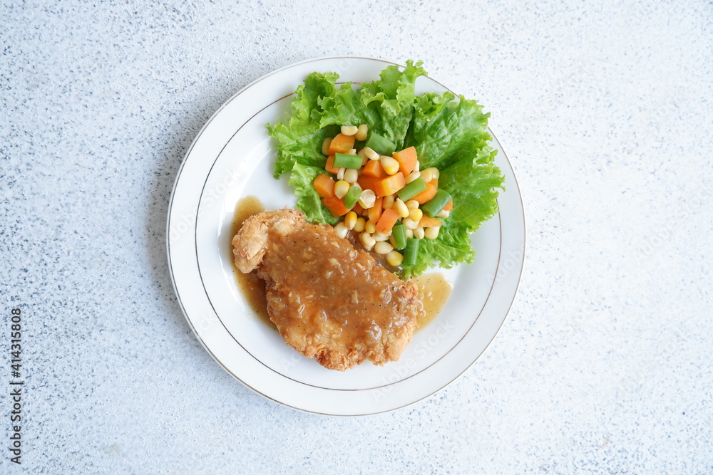a plate of crispy chicken steak and vegetables with black pepper sauce in white background a plate of crispy chicken steak and vegetables with black pepper sauce in white background