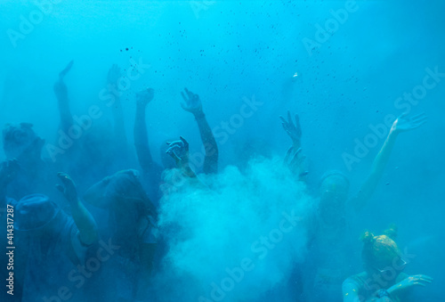 silhouettes of people raising their hands in blue smoke from powdered color dyes, background.