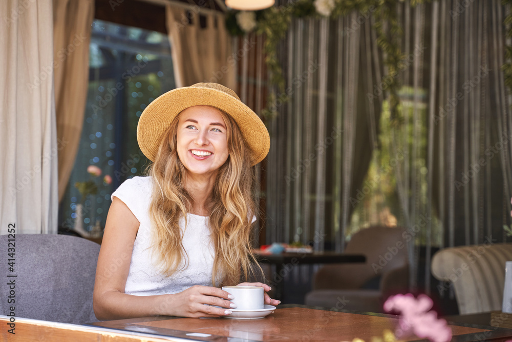 Young woman drinking coffee at street cafe. Staycation tourist. Female person in summer hat. Positive emotion. Smiling people. Dreaming about vacation
