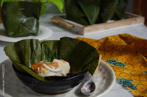a traditional dessert wrapped with leaves named pis kopyor in a plate on the table